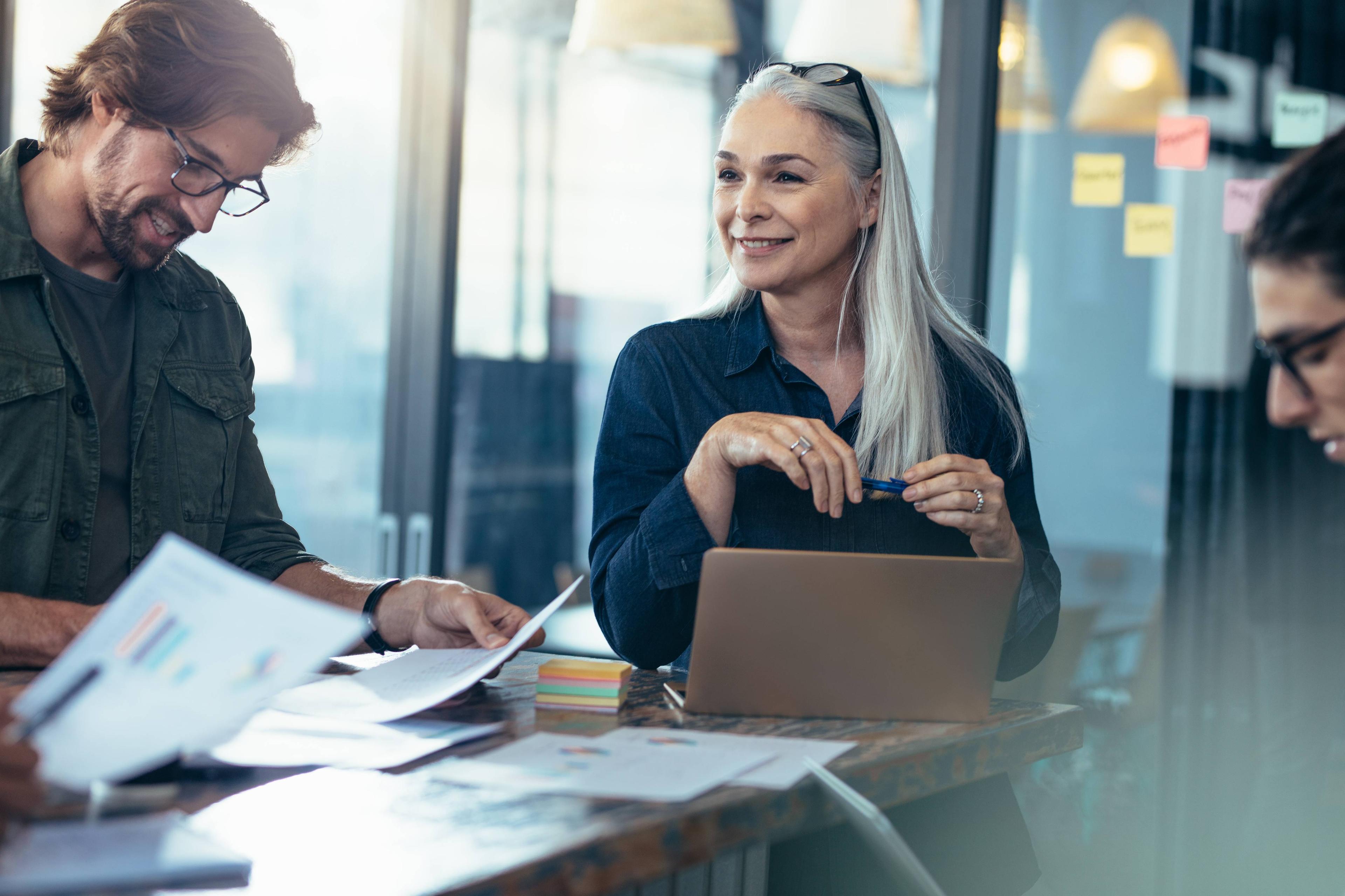 woman using laptop and working with two other people