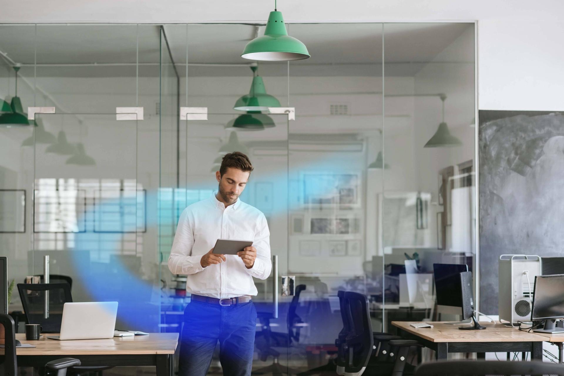 Man standing in office with a tablet